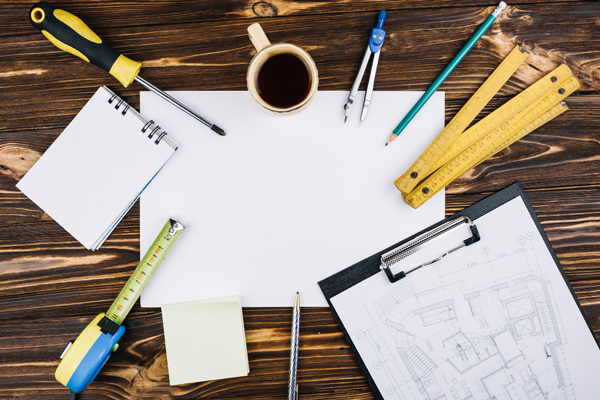 Construction tools and paper on wooden table: A collection of tools and documents for construction projects.