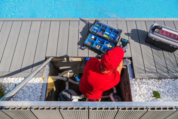 A man in a red shirt diligently working on a pool, ensuring its cleanliness and maintenance.